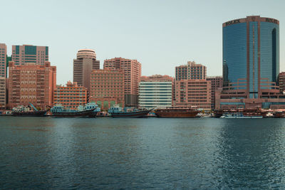 Buildings by river against clear sky