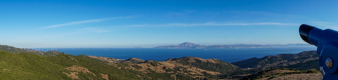 Panoramic view of sea and mountains against blue sky