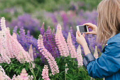 Rear view of woman photographing with mobile phone