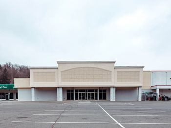Empty road by building against sky