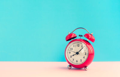 Close-up of clock on table against blue background