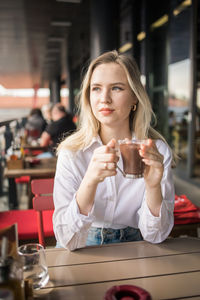 Young woman using mobile phone while sitting at restaurant
