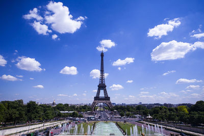 Communications tower in city against cloudy sky
