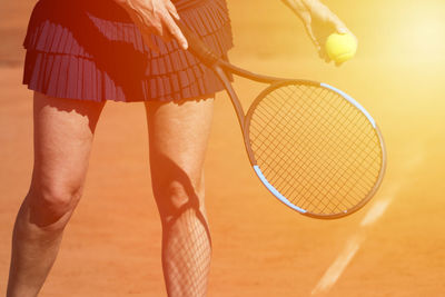 Midsection of woman playing tennis in court