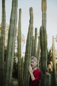 Mature man with eyes closed touching cactus plant in garden