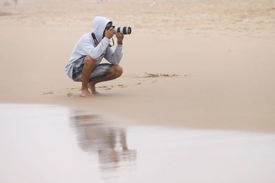 Full length of man photographing at beach