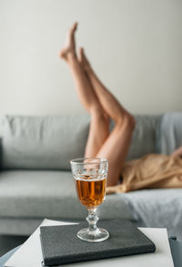 Low section of woman standing on sofa at home