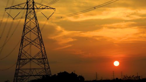 Low angle view of silhouette electricity pylon against sky during sunset