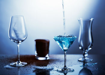 Close-up of drink being poured in glass with ground coffee and feather on table