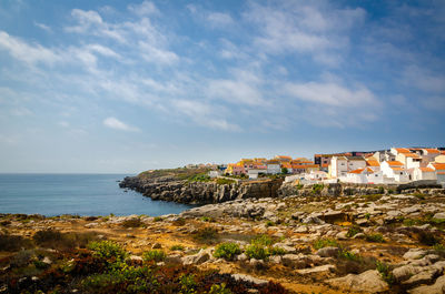 Buildings by sea against sky