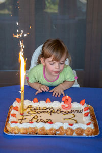 Cute girl blowing candles in cake at home interior