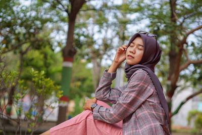 Young woman standing against trees
