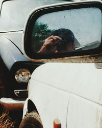 Reflection of man on side-view mirror of car