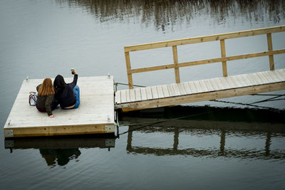 Rear view of woman sitting by lake