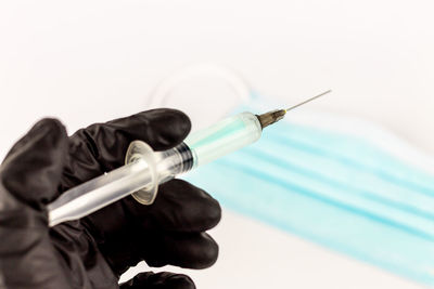 Close-up of hand holding cross against white background