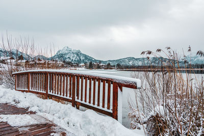 The hopfensee with the allgäu alps in winter. germany. in the foreground a snow-covered bridge.