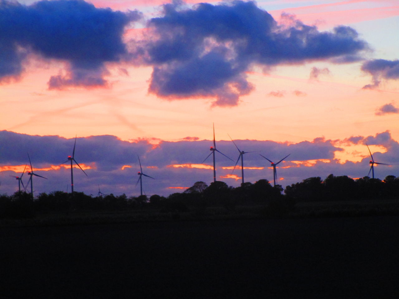 SILHOUETTE OF WIND TURBINES ON FIELD AGAINST SKY DURING SUNSET