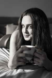 Portrait of young woman using mobile phone on bed at home