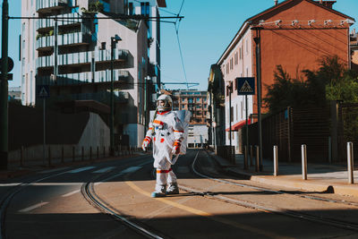 Full length of boy standing on street against buildings in city