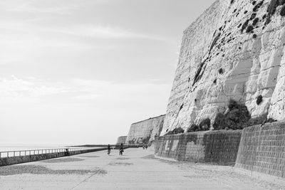 Stone wall by sea against sky