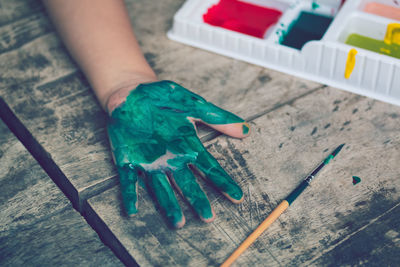 High angle view of human hand with painted hand on table