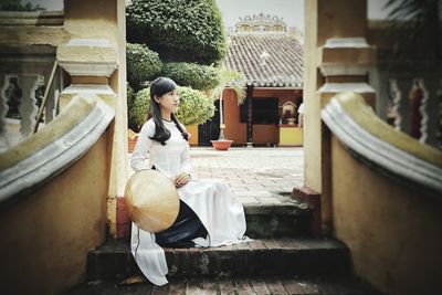 Woman sitting on staircase outside building