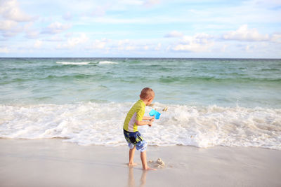 Rear view of boy standing at beach