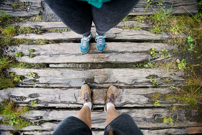 Low section of couple standing on wooden footpath