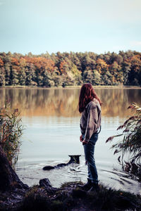 Woman standing at lakeshore against sky