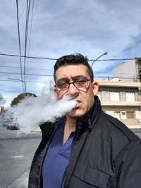 Mature man smoking against sky