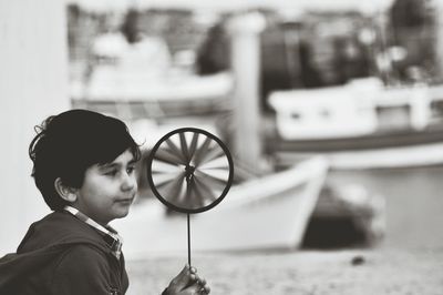 Boy holding pinwheel toy while sitting in city