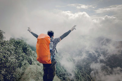 Rear view of men standing on mountain against sky