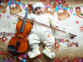 Full length of cute baby with violin on bed at home