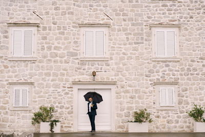 Full length of man standing against building wall