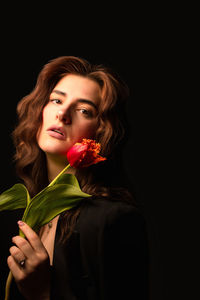 Portrait of young woman against black background