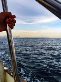 Close-up of hand against sea