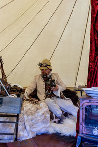 Man holding camera while sitting in tent