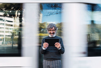 Mature man using digital tablet while waiting for train. businessman waiting for train