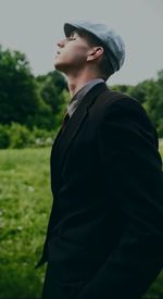 Young man looking away while standing on field