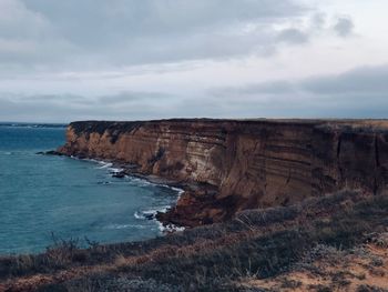 Rock formations by sea against sky