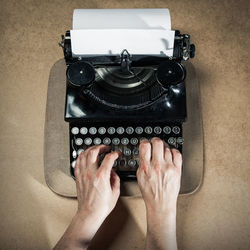 Cropped hands of man typing on typewriter at table