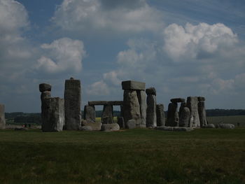 Old ruins on field against cloudy sky