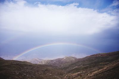 Scenic view of rainbow over mountains against sky