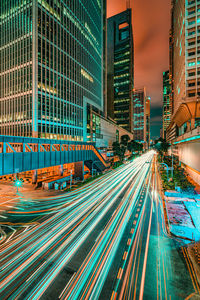 Light trails on city street amidst buildings