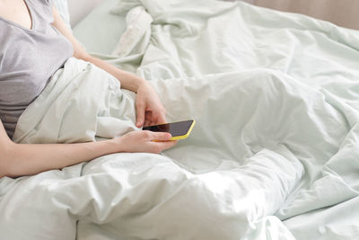 Midsection of man using mobile phone on bed