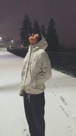 Woman standing on snow covered tree at night