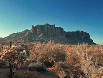 Rock formations on landscape against clear blue sky