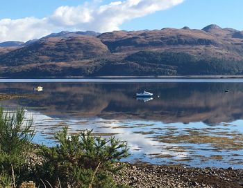 Boat in calm lake against mountain range