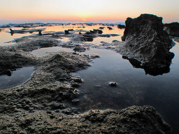 Rocks in sea at sunset