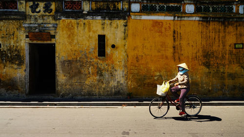 Man riding bicycle on road against building